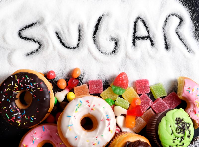 mix of sweet cakes, donuts and candy with sugar spread and written text in unhealthy nutrition